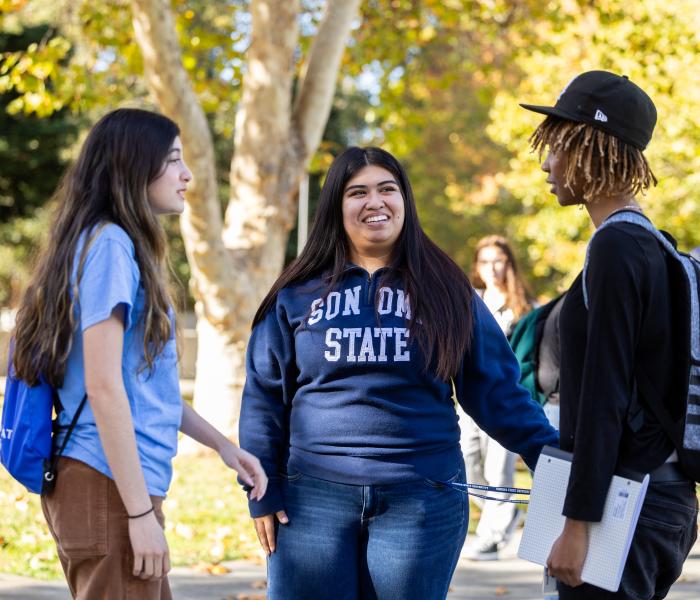 Student wearing SSU sweatshirt talking to two other students outside