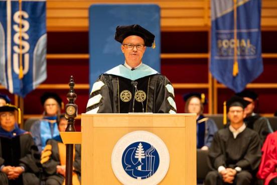 Dr. Nathan Evans standing at a podium at commencement