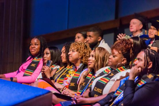 Students sitting in graduation regalia at Black Graduation