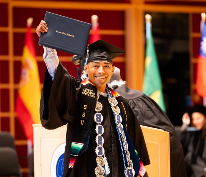 Student holding diploma holder in grad regalia