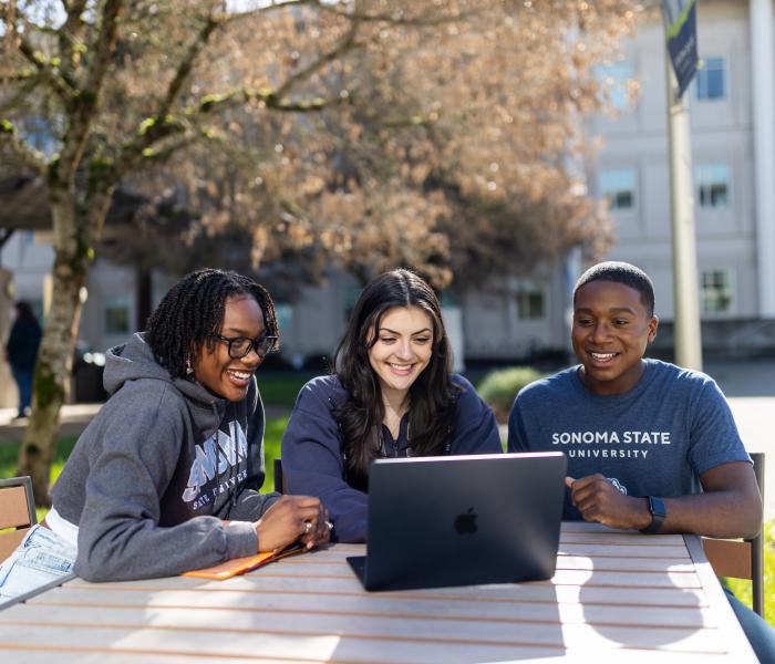 Three students looking at a computer