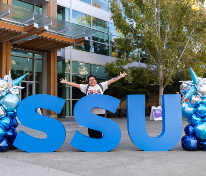 Student holding hands up in front of SSU large letters