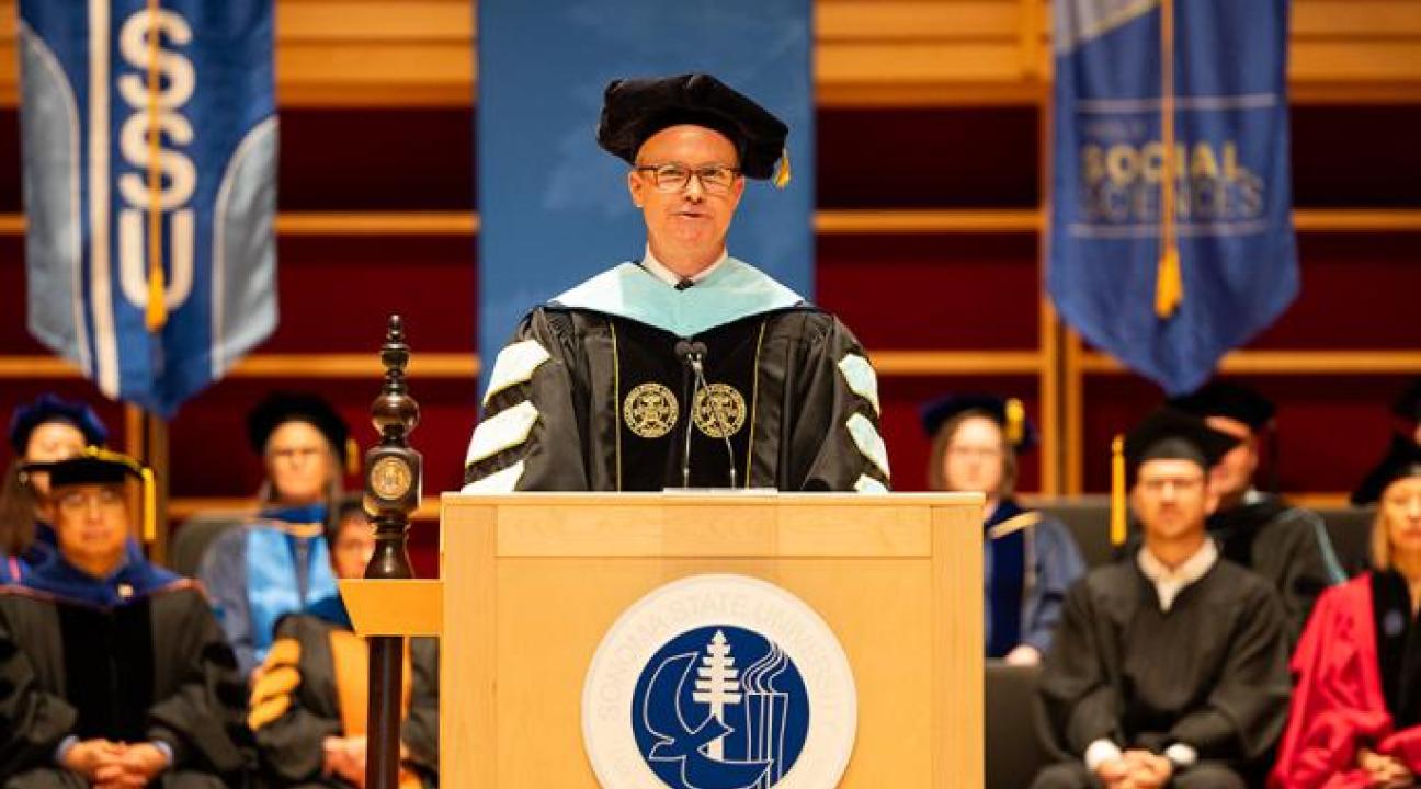 Dr. Nathan Evans standing at a podium at commencement