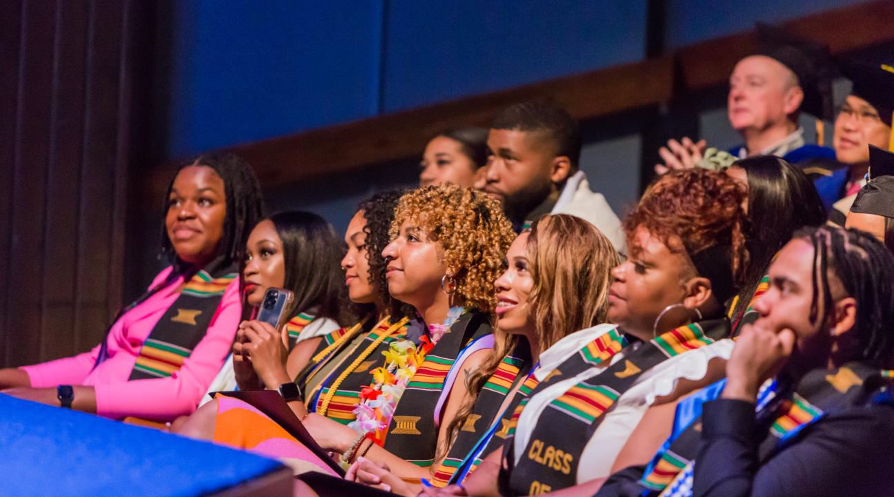 Students sitting in graduation regalia at Black Graduation