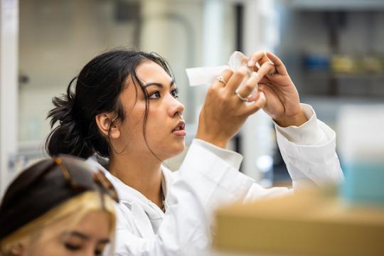 Student in science class looking at specimen on glass