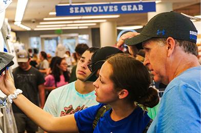 Two people looking at SSU hats on a rack