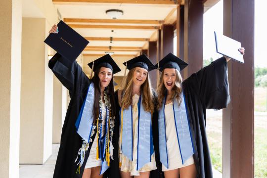 Student holding diploma holder in grad regalia