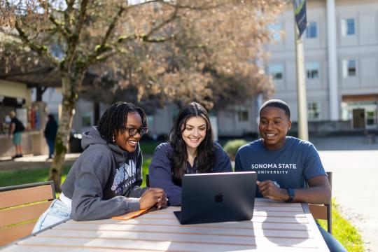 Three students looking at a computer