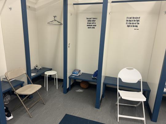 Locker room with a couple chairs and bars to hand clothing