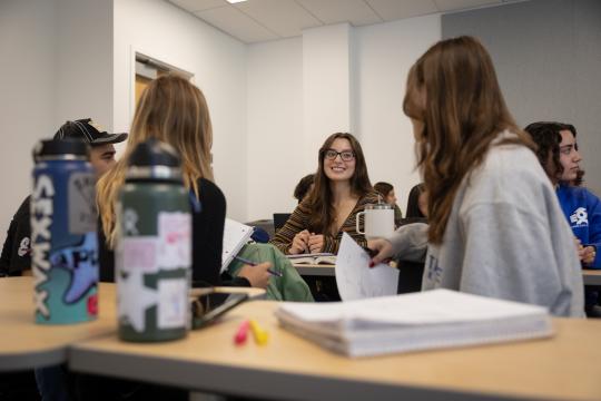 Students sitting in a group of four in a classroom interacting with each other