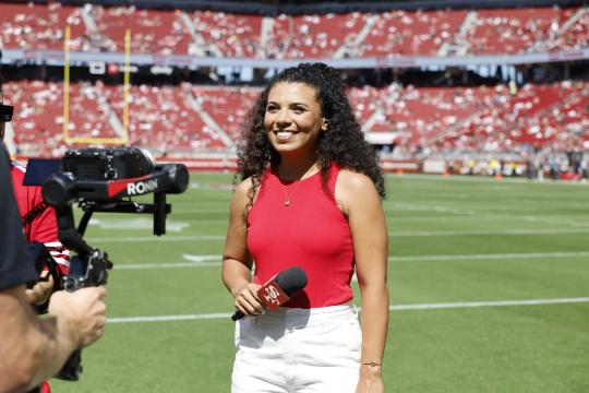 Aubrie Tolliver standing on Levi Stadium Field with a microphone in hand