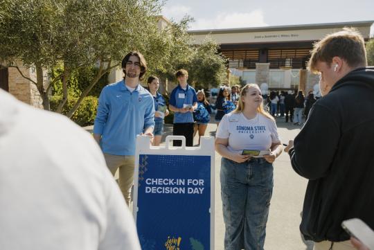 Sonoma State University student ambassador Denise Bevis (right, facing camera) greets prospective students at SSU Decision Day 2024