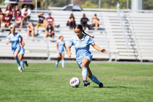 An SSU student kicking a ball while playing on the Women's Soccer team