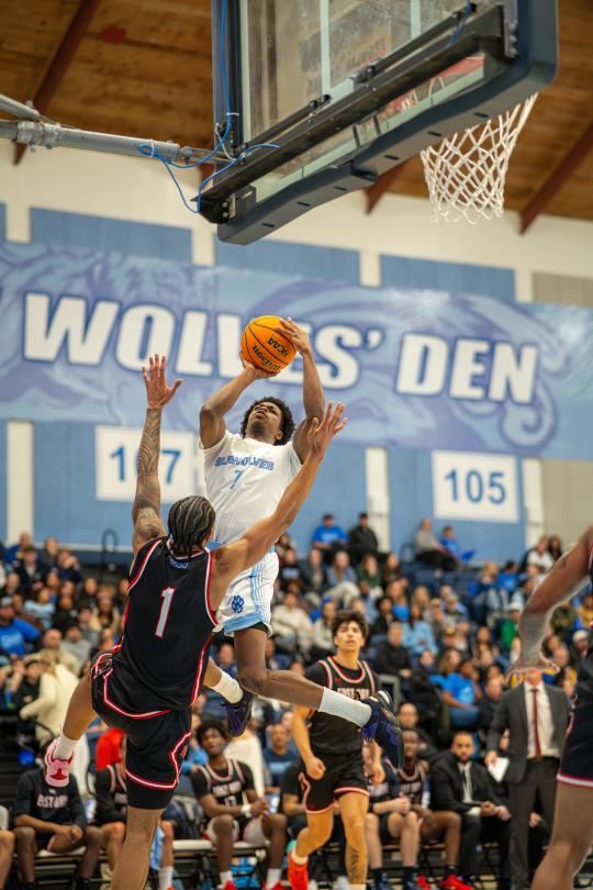 An SSU student dunking a basketball while playing on the Men's Basketball team